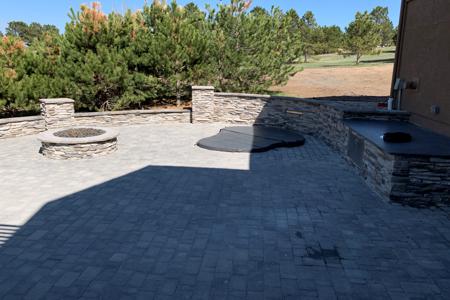 Monument, Colorado paver patio with a granite slab for serving and a veneer sitting wall for entertainment, built around an in ground hot tub
