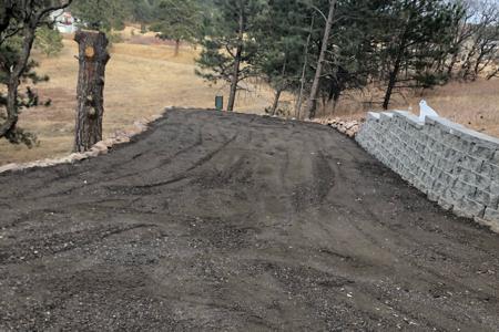 Excavating in Monument, Colorado for a new parking area and turn around in a driveway with the installation of a new segmental retaining wall and crushed apshlat.