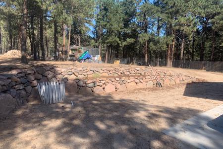 Boulder retaining wall around a hot tub and to divert water in Black Forest, Colorado