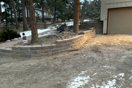 Retaining wall Monument, Colorado. The installation of a segmental retaining wall to keep the landscape from falling onto the driveway and creating more area for entering the garage door.