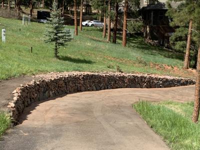 Boulder retaining wall to stop the erosion along a driveway in Perry Park Colorado
