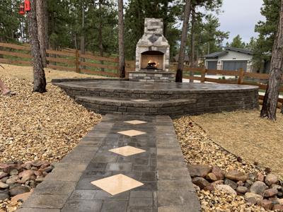 Segmental retaining wall holding up a paver patio for the gas fired fireplace in the back yard in Monument Colorado